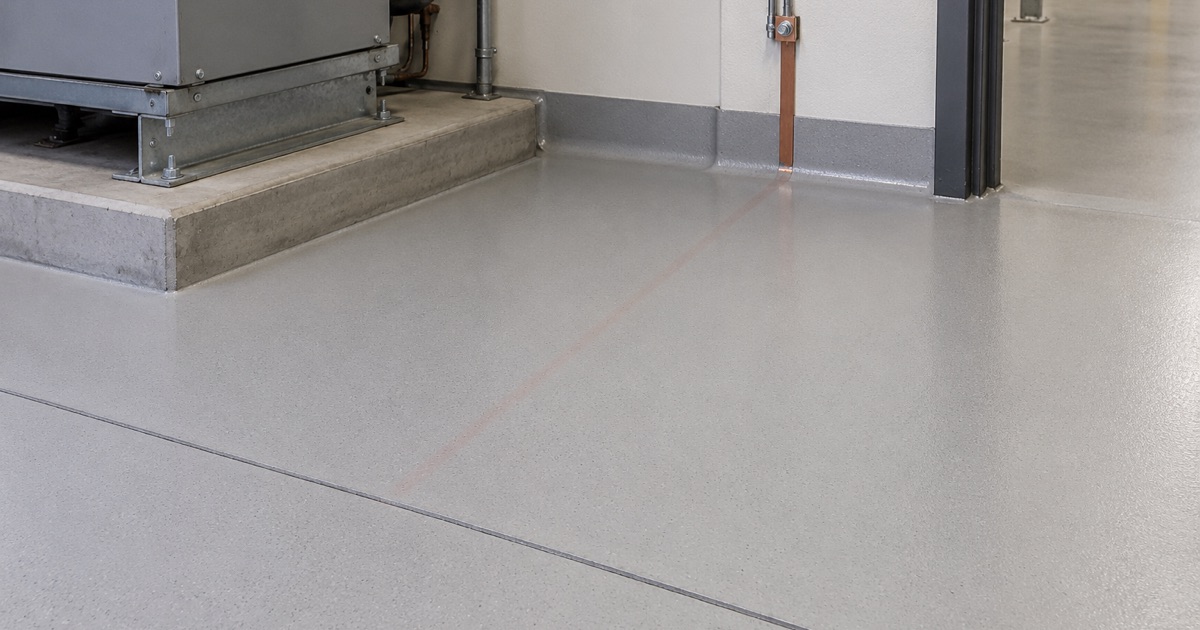 A smooth gray floor with coved edges beneath industrial equipment.